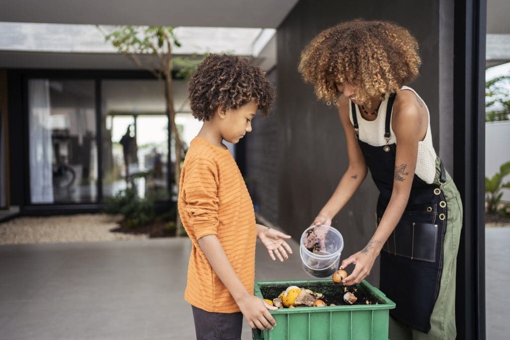 Young woman and her younger brother making compost from kitchen food leftovers into rich organic soil fertilizer. Earth Day Resolutions