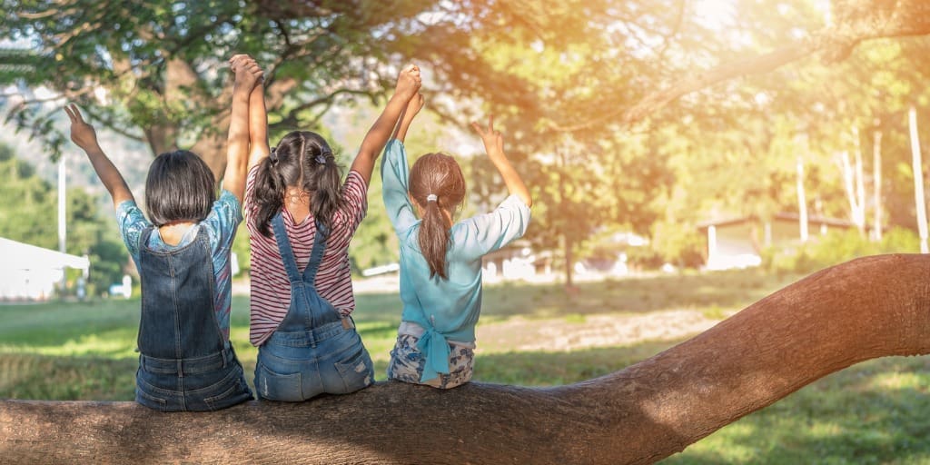 Three girls sitting on login the yard