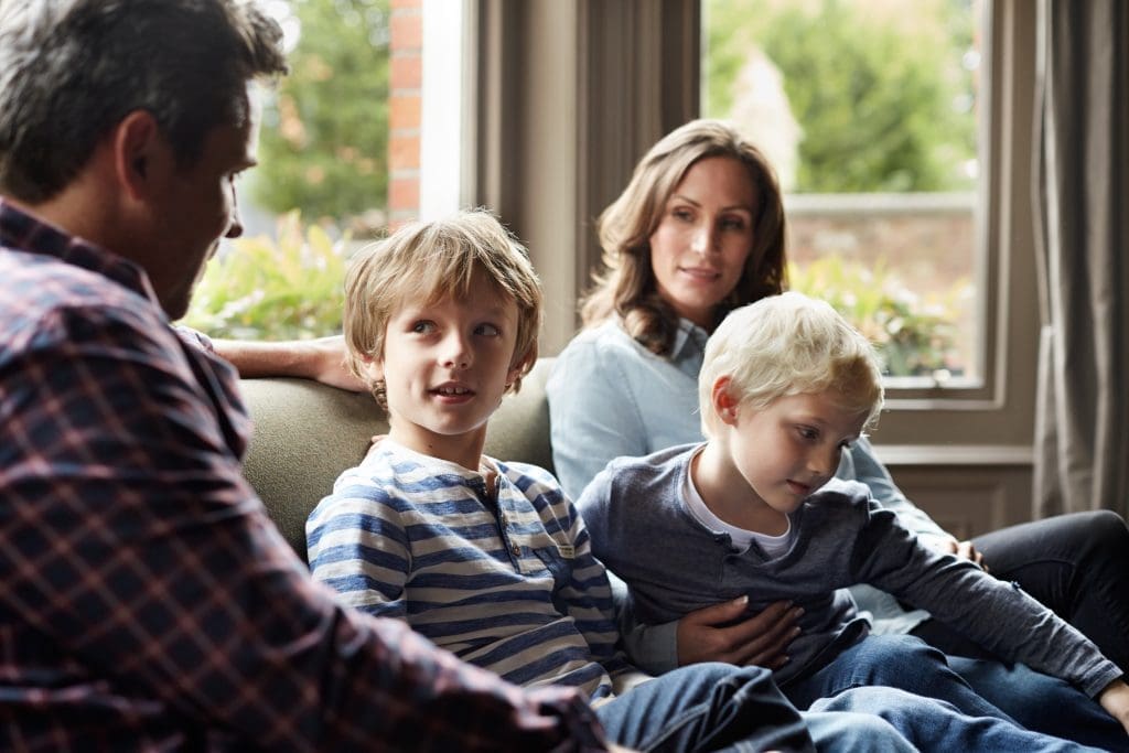 family of four sitting together on their living room sofa