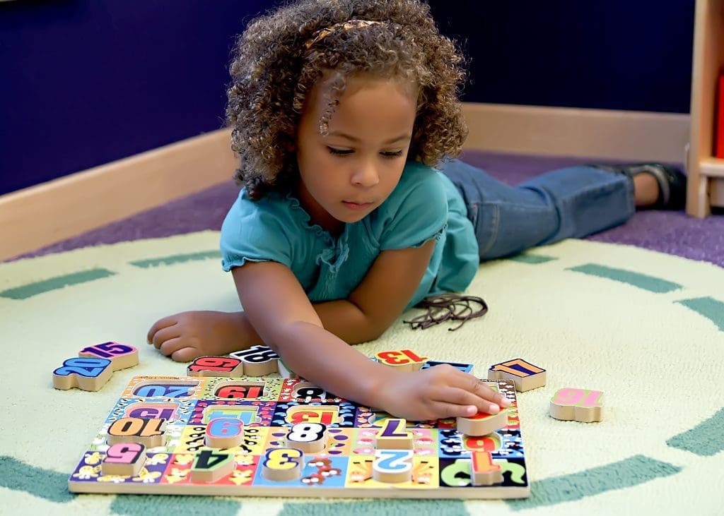 young preschool girl works on a numbers puzzles executive function