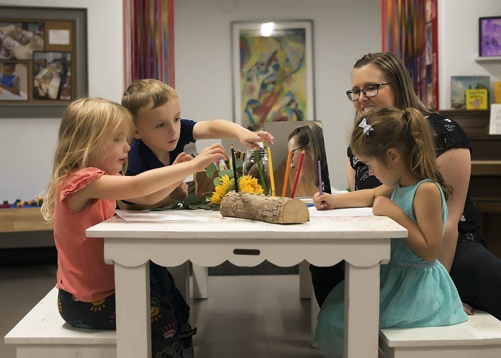teacher works with two girls and one boy at a small classroom table - executive function