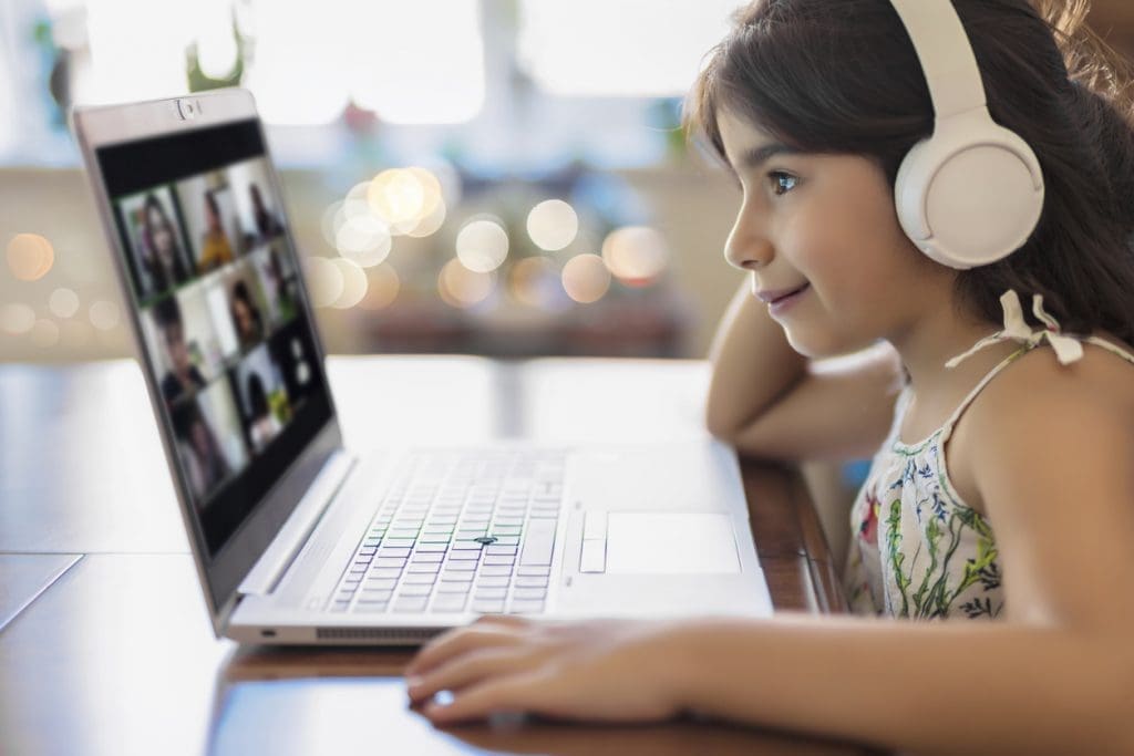 Girl student video conference e-learning with teacher on computer in living room at home.
