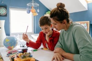 Photo of a young boy being homeschooled by his mother in his bedroomAdvice for New Homeschooling Moms