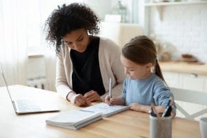 Stepmother helps stepdaughter with her homework. Managing back to school between two homes.