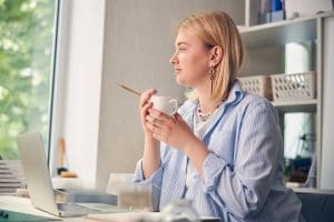 Blonde woman at desk having coffee. Going back in the office