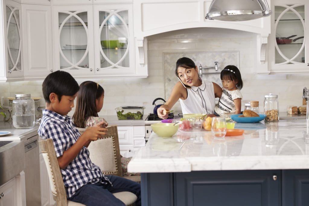 juggle it all: Busy Mother Organizing Children At Breakfast In Kitchen