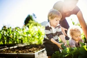Two toddlers helping their mom in the garden