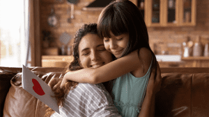 young girl giving her mom a hug and a card