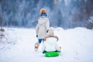 Minnesota Winter - one little girl pulling another on a sled