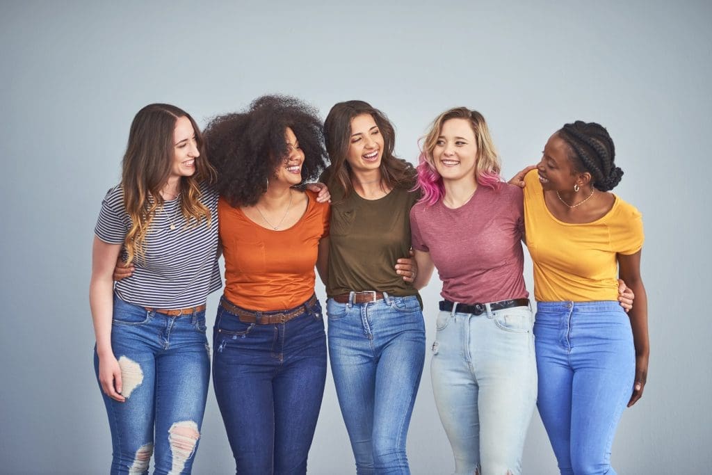 Studio shot of a group of attractive young women embracing against a gray background. 5 Types of Moms