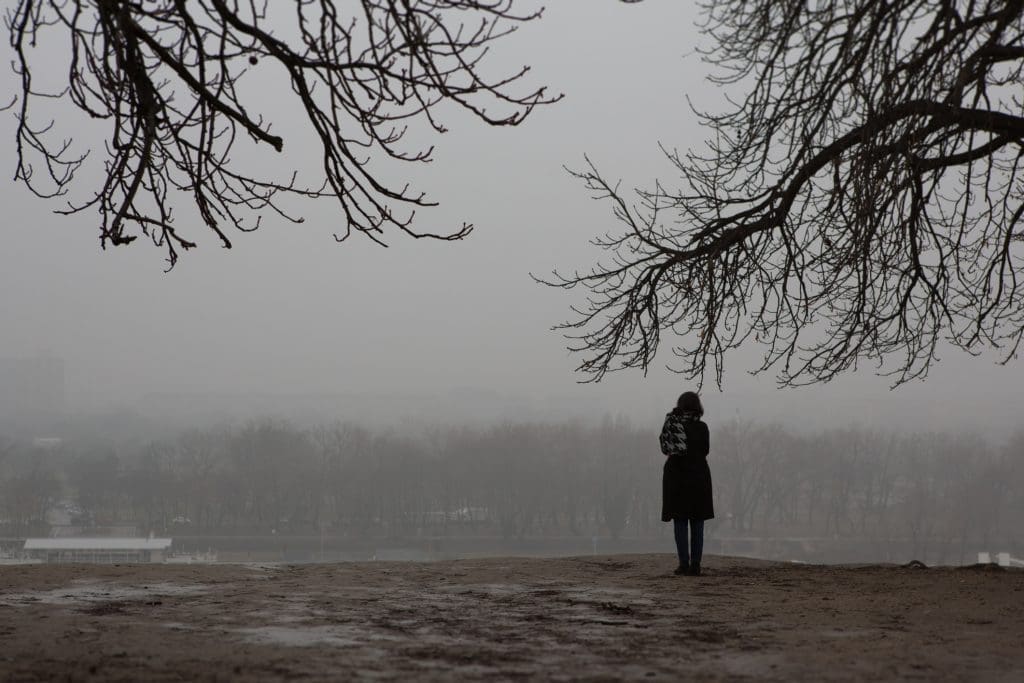 woman standing alone in the park on gloomy day. 5 winter blues tips