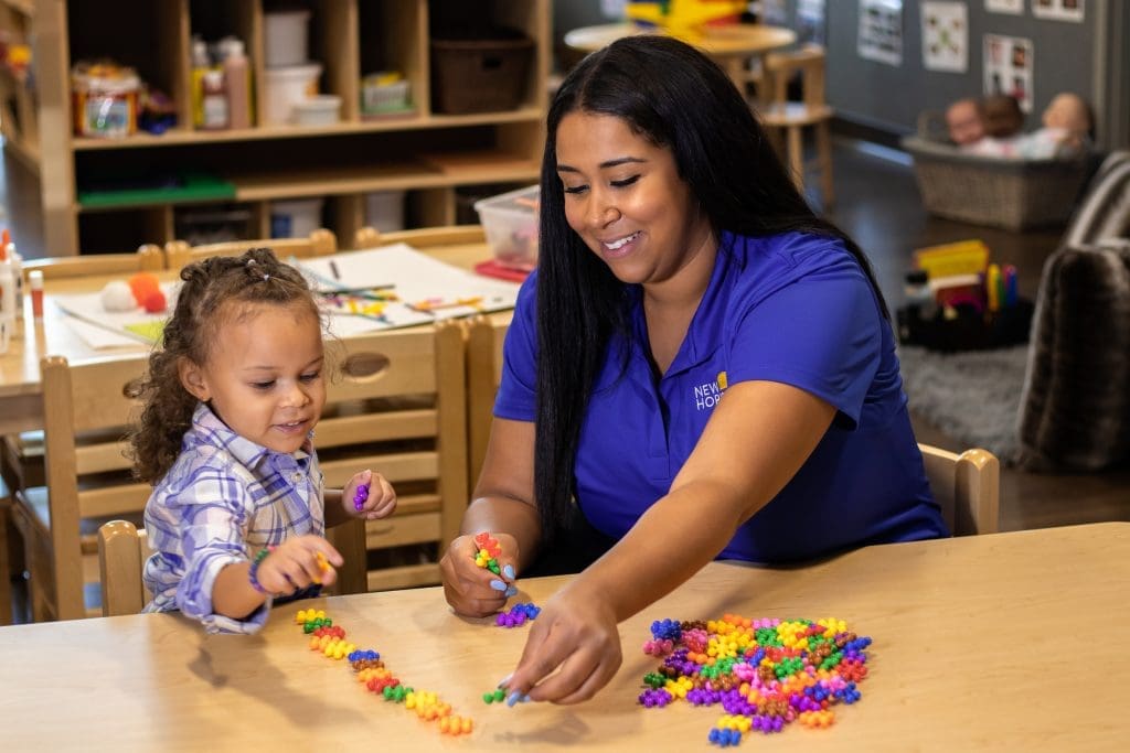 Female Preschool teacher working with 3 year old girl - early childhood education