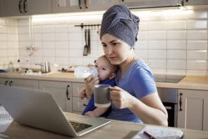 Mother with baby paying bills online in kitchen - morning routine reality check