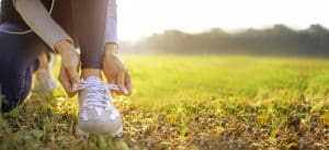 young woman runner tying her shoes preparing for a jog outside at morning - hobbies to replace social media