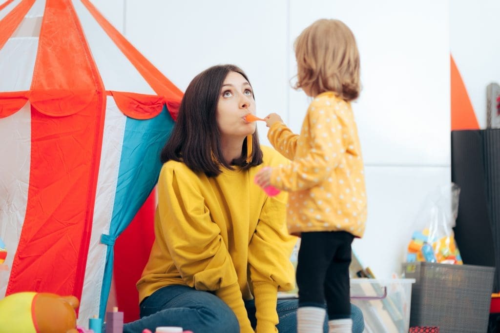 Girl pretending to spoon feed her mom reversing roles - pretend play