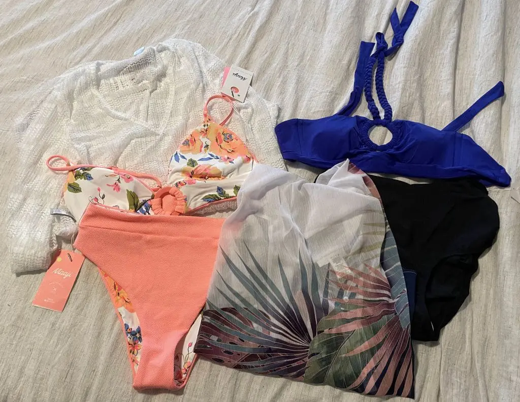 2022 swimsuit trends - collection of swimsuits and coverups on a bed