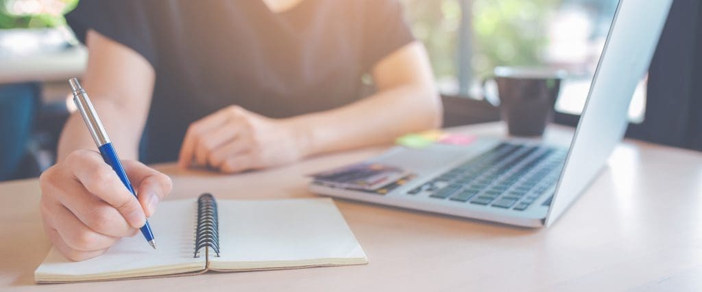 writing your pandemic story - Business woman hand is writing on a notepad with a pen.