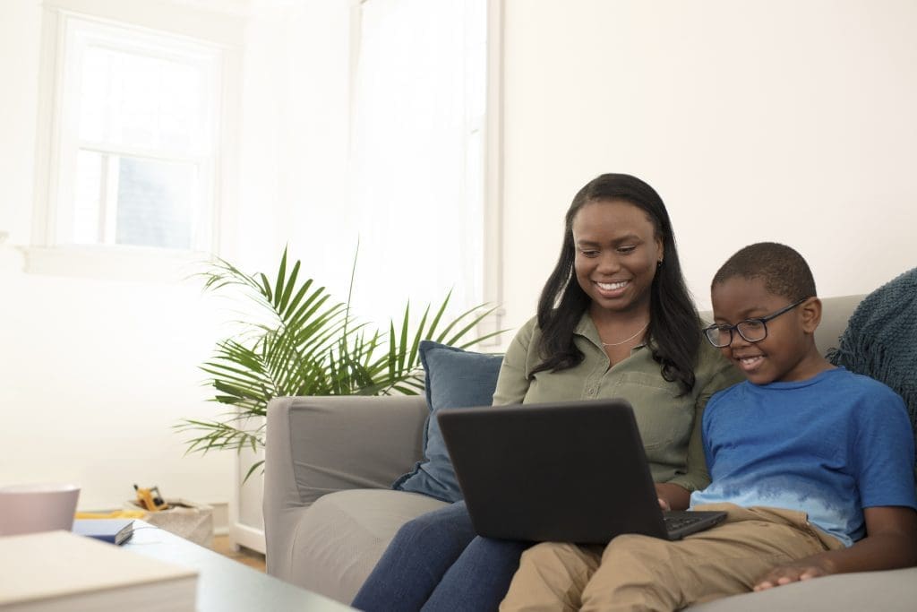 mother and son sitting on couch on their laptop