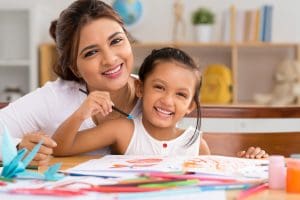 Portrait of happy mother and daughter painting with gouache - mommy and me class