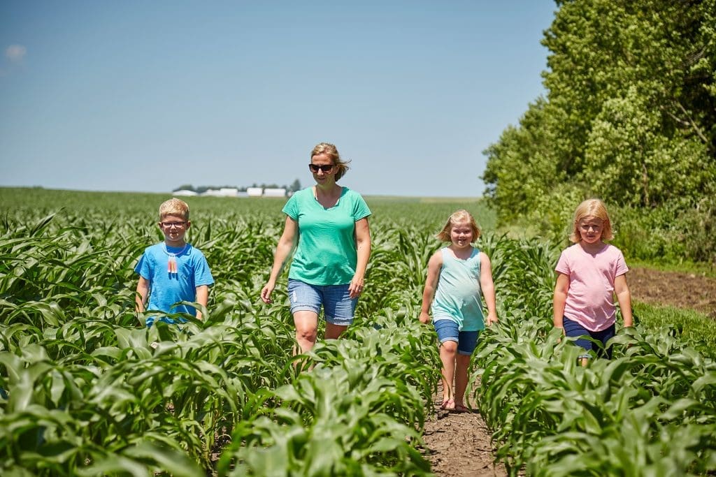 woman farmer and her three children walking along their crops. Farmer Stories